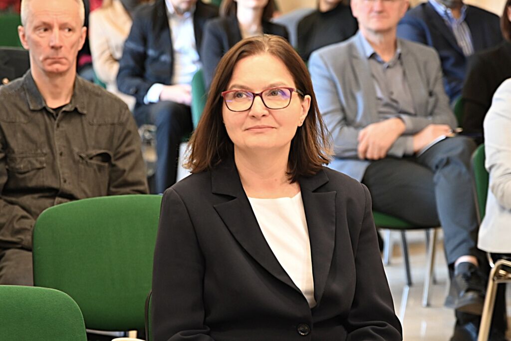 Wiceminister klimatu i środowiska Anita Sowińska siedzi na sali konferencyjnej.
