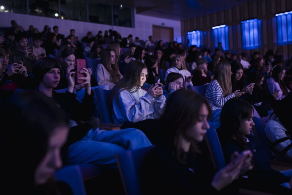 Młodzież siedzi na sali